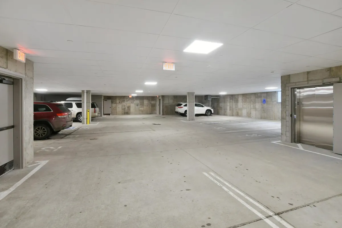 An interior view of the underground parking structure, with vehicles parked in well-lit spaces and easy pedestrian access to the building. The scene underscores security and convenience for guests.